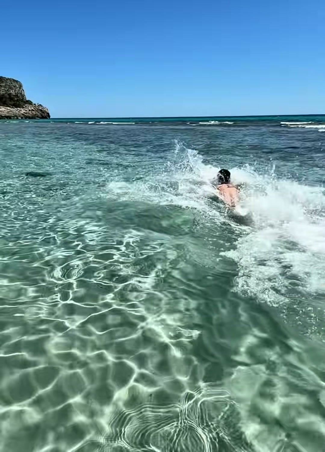 Agua transparente y turquesa en la playa de Son Bou, con alguien nadando